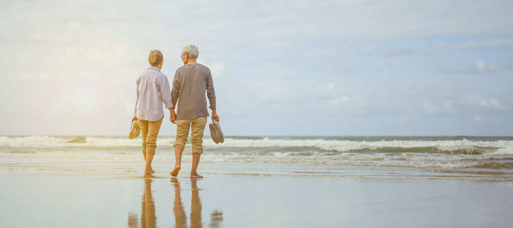 Older adults walking on the beach near Seal Beach while researching Leisure World Seal Beach